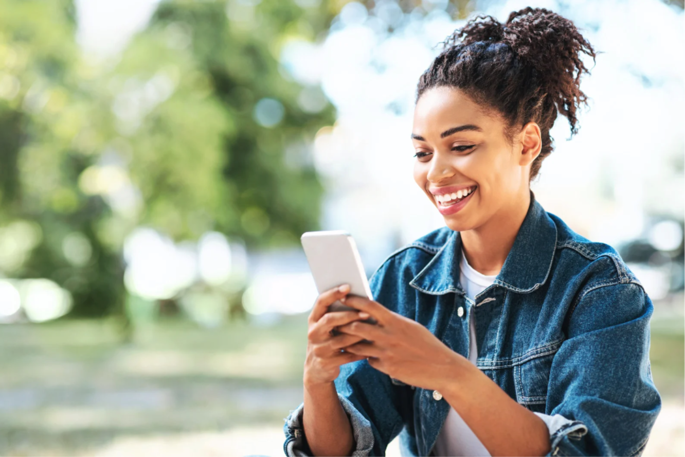 Mulher sorrindo e utilizando o app em um ambiente aberto.